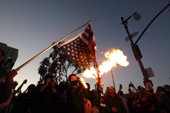 지난 2020년 5월 플로이드 피살 사건 직후 LA 다운타운에서 벌어진 항의 시위에서 참가자가 성조기에 불을 붙이고 있다. 김상진 기자