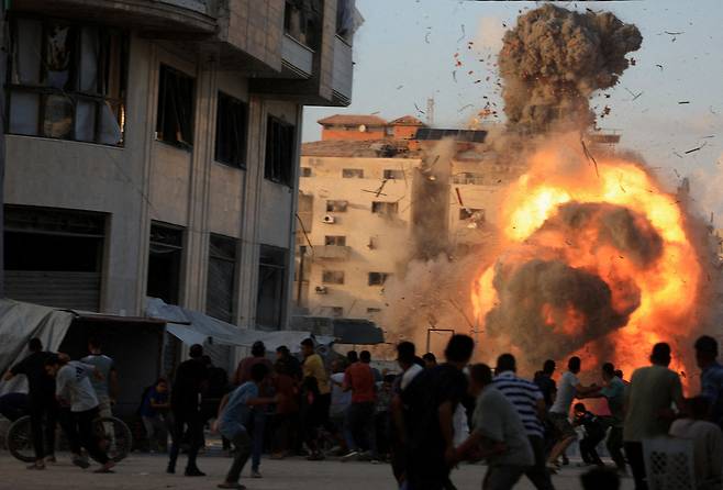 7일(현지시간) 가자시티에서 이스라엘의 공습으로 주거용 건물이 무너져 내리자 팔레스타인 주민들이 연기와 불길이 치솟는 현장을 지켜보고 있다. 로이터연합뉴스