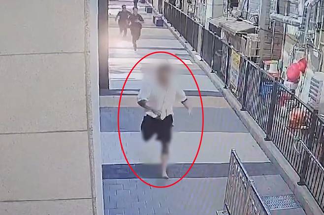 A fugitive wanted for violent crimes throws off his slippers and runs from an identification check by police in Busan on Sept. 4. [BUSAN METROPOLITAN POLICE]