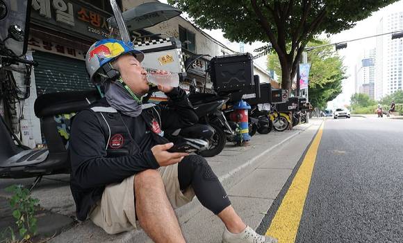 퀵커머스 서비스가 확장하면서 배달기사들의 안전 문제도 대두되고 있다. 서울 시내에서 한 배달 노동자가 물을 마시며 더위를 식히고 있다. [사진=연합뉴스]