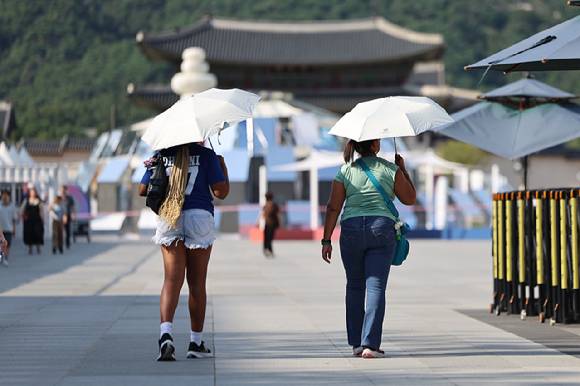 서울 한낮 기온이 33도까지 오르며 더운 날씨를 보인 21일 서울 종로구 광화문광장에서 관광객들이 양산을 쓰고 이동하고 있다. 2025.8.21  [사진=연합뉴스]