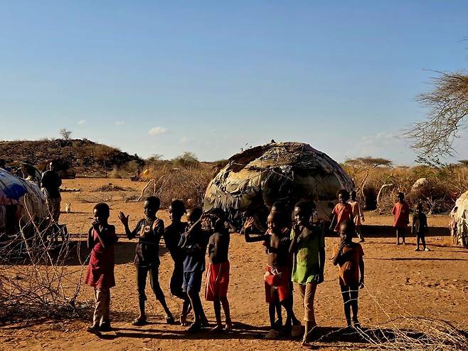 렌딜레 부족 아이들이 전통 원형초가 앞에서 미소를 짓고 있다.
