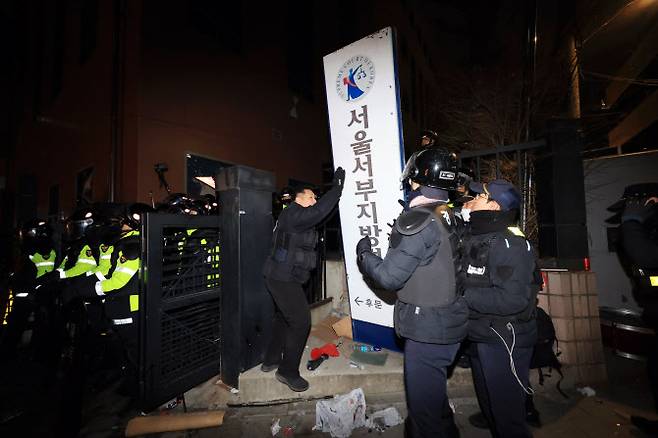 서울 마포구 서울서부지방법원을 습격한 지난 1월 19일 오전 경찰이 서부지법 후문에서 쓰러진 현판을 세우고 있다. [연합]