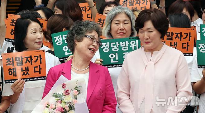 [부산=뉴시스] 하경민 기자 = 61년 전 성폭행에 저항하는 과정에서 가해자의 혀를 깨물어 1.5㎝가량 절단하는 상해를 입혔다는 이유로 가해자보다 더 중한 형을 선고받았던 최말자(79)씨가 재심에서 무죄를 선고받았다.  10일 부산 연제구 부산지방법원 앞에서 최씨가 여성단체 회원들과 함께 무죄 선고에 기뻐하고 있다. 2025.09.10. yulnetphoto@newsis.com