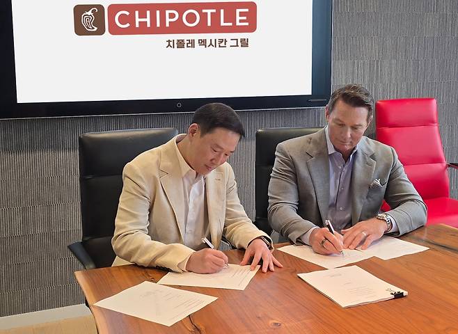 Scott Boatwright (right), CEO of Chipotle Mexican Grill, and Hur Hee-soo, executive vice president of SPC Group, sign the joint venture agreement in the US. (SPC)