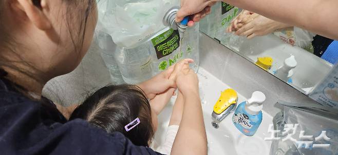 어린이집 한 원생이 접이식 물주머니에 보관된 물로 손을 씻고 있다.  임성민 기자