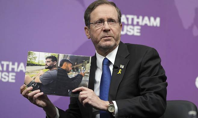 10일(현지시간)&nbsp;이츠하크 헤르초그 이스라엘 대통령이 영국 런던&nbsp;왕립국제문제연구소(RIIA), 일명 ‘채텀하우스’에서 연설하는 도중 하마스에 붙잡혀 인질이 된 이스라엘 형제의 사진을 꺼내 청중에게 보여주고 있다. AP연합뉴스