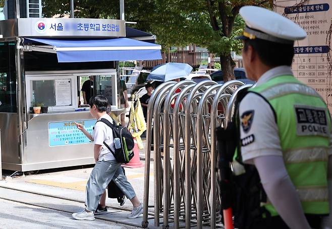 Police officers stand guard as elementary students head home from school in Seodaemun District, western Seoul, on Sept. 8. [NEWS1]