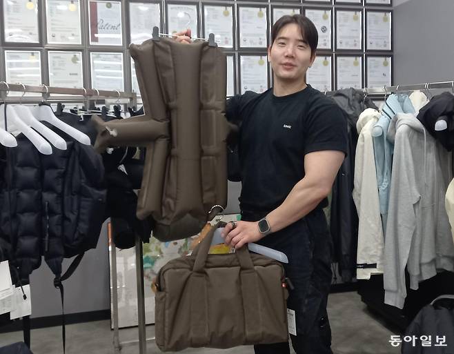 이재호 커버써먼 대표이사가 서울 성동구 성수동 소재 본사 사무실에서 공기를 충전재로 사용한 ‘에어 스마트 원단’으로 만든 노트북PC용 가방과 그 가방에 들어간 부품을 함께 들어보이고 있다. 벽면에는 특허증이 가득하다. 허진석 기자 jameshur@donga.com