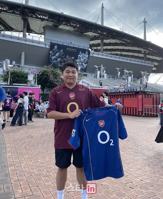 아스널 유니폼을 입은 유중안 씨가 또 다른 아스널 유니폼을 들고 사진을 찍고 있다.