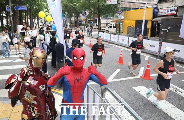 14일 오전 서울광장에서 열린 '마블런 서울 2025' 행사에서 아이언맨과 스파이더맨으로 분장한 참가자가 러너를 응원하고 있다. /디즈니코리아