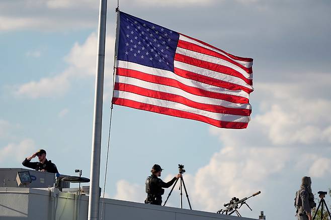 무장한 보안 요원들이 11일(현지 시간) 찰리 커크의 시신을 담은 관이 들어온 피닉스 스카이하버 공항을 경계하고 있다. 성조기와 저격용 총이 보인다. 피닉스=AP 뉴시스
