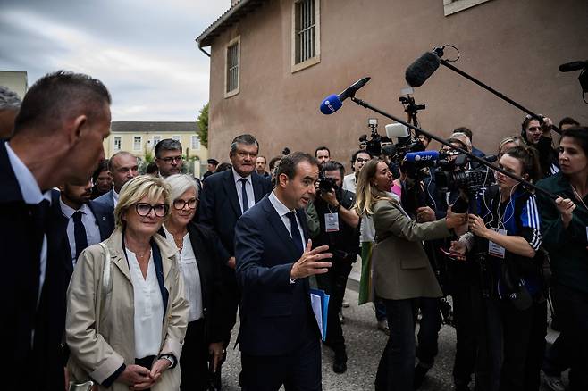 세바스티앵 르코르뉘(가운데) 신임 프랑스 총리가 13일 프랑스 중동부 마콩의 보건센터를 방문한 뒤 떠나면서 기자들의 질문에 답하고 있다. 긴축 예산 반발 시위 속에 출범한 르코르뉘 총리는 이날 공휴일 폐지안을 철회한다고 밝히며 민심 달래기에 나섰다. /AFP 연합뉴스