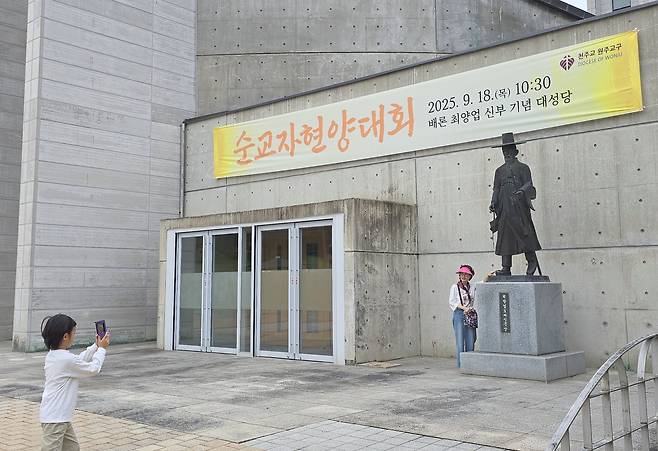 ‘케데헌’ 사자보이즈 진우를 닮은 배론성지 최양업 신부 동상 앞 인증샷. 손자가 명랑한 할머니의 인증샷을 찍어주고 있다.