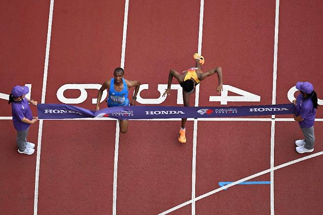 탄자니아의 심부(사진 왼쪽 파란색 유니폼)가 15일 일본 도쿄에서 열린 2025 세계육상선수권 남자 마라톤에서 결승선을 통과하고 있다. 독일의 페트로스도 거의 동시에 결승 테이프를 끊었지만, 사진 판독 결과 심부가 0.03차로 우승했다. 연합뉴스