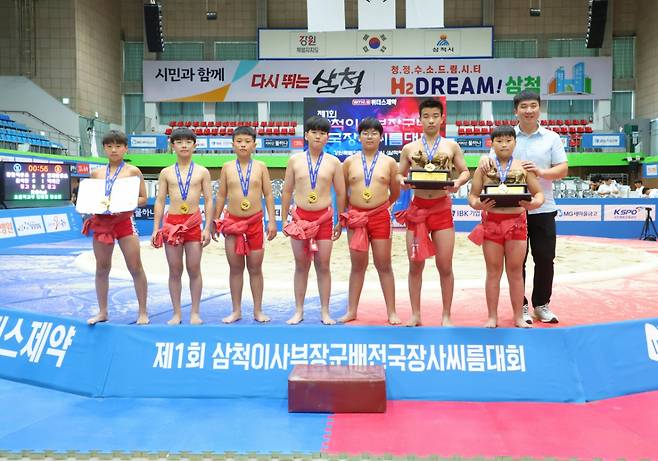 강원특별자치도 삼척시 삼척체육관에서 열린 '제1회 삼척이사부장군배전국장사씨름대회' 초등부 단체전 우승을 차지한 원통초등학교(강원특별자치도)가 김주현 감독(오른쪽)과 함께 기념사진을 찍고 있다. /사진=대한씨름협회 제공