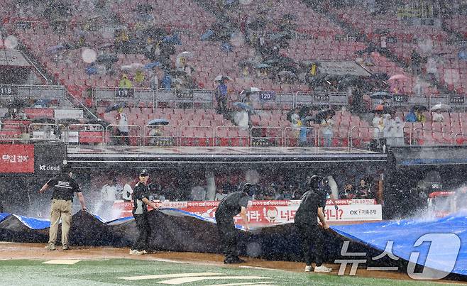 16일 오후 경기 수원시 장안구 KT위즈파크에서 열린 '2025 신한 SOL 뱅크 KBO리그' LG 트윈스와 KT 위즈의 경기, 3회말 우천으로 경기가 중단돼 구단 관계자가 방수포를 덮고 있다. 2025.9.16/뉴스1 ⓒ News1 김영운 기자