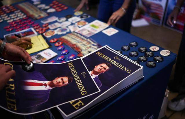 미국 애리조나주 템피의 애리조나 주립대학교 캠퍼스 데저트 파이낸셜 아레나에서 15일 우익 활동가 찰리 커크를 추모하는 집회가 열린 가운데 참석자들이 전단지와 버튼을 들고 있다. 템피=AFP 연합뉴스