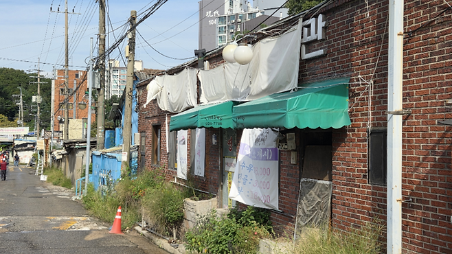 백사마을에서 영업하던 한 식당 앞에 빛바랜 현수막이 걸려 있다. [권민선 기자]