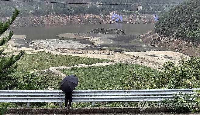 비 내리는 강릉시 상수원 오봉저수지 (강릉=연합뉴스) 유형재 기자 = 폭우가 쏟아진 17일 한 강릉시민이 강원 강릉지역 생활용수의 87%를 공급하는 상수원 오봉저수지를 바라보고 있다. 2025.9.17 yoo21@yna.co.kr