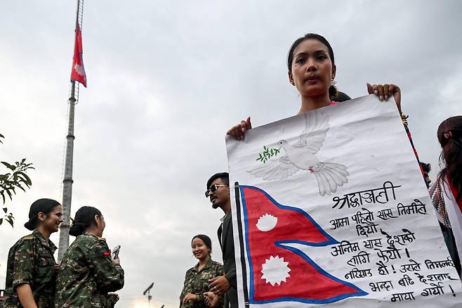 국가생도단(NCC) 생도들이 2025년 9월 17일 카트만두의 마이티가르 만달라에서 최근 시위 중 충돌로 사망한 사람들을 추모하는 '국가 애도의 날'을 기념하며 묵념하는 동안 포스터를 들고 있다. /연합뉴스