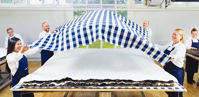 해스텐스의 장인들이 말총, 양모를 여러 겹 포갠 톱 매트리스를 블루체크 천으로 덮는 작업을 하고 있다. 해스텐스 제공