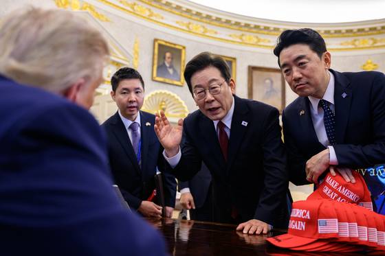 South Korean President Lee Jae Myung, second from right, and presidential chief of staff Kang Hoon-sik, far right, speak with U.S. President Donald Trump, far left, who is seated at the Resolute desk in the Oval Office of the White House in Washington on Aug. 25. [THE WHITE HOUSE]