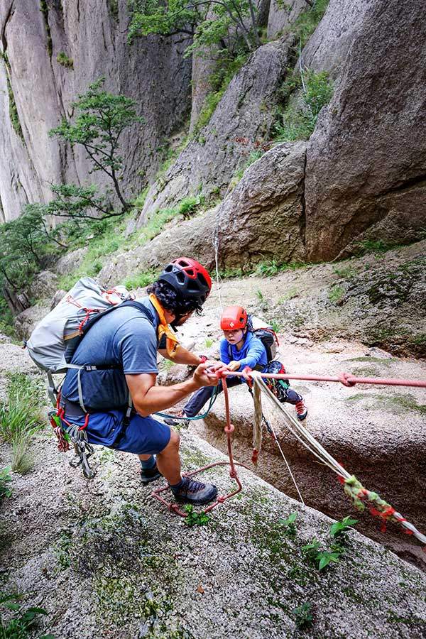 박민구 강사가 고정로프를 이용해 뜀바위 건너기를 도와주고 있다. 절벽 아래로 데굴데굴 굴러떨어질까 무서웠다.