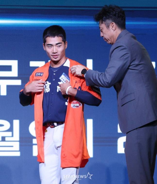 '2026 KBO 신인 드래프트'가 17일 서울 송파구 롯데호텔 월드 크리스탈볼룸에서 열렸다.  오재원(유신고)이 전체 3순위로 한화에 지명된 후 손혁 단장의 도움으로 유니 폼을 입고 있다.