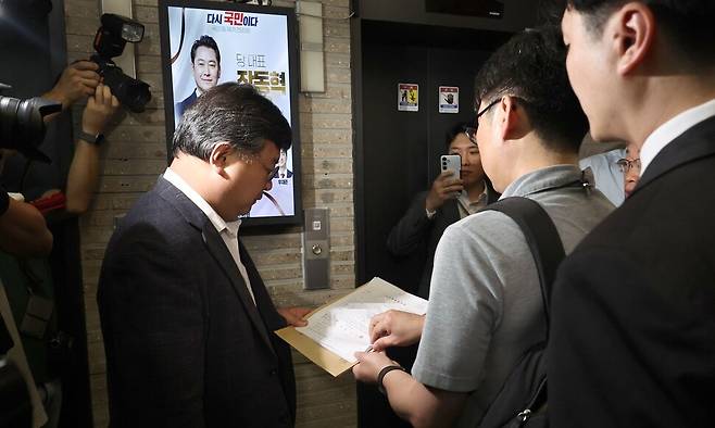 18일 서울 여의도 국민의힘 중앙당사 현관 엘리베이터 앞에서 김건희 특검팀이 제시한 압수수색 영장을 국민의힘쪽 변호사가 읽고 있다. 윤운식 선임기자 yws@hani.co.kr