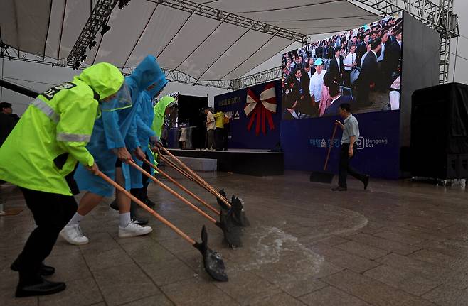 2025년 9월17일 오전 서울 여의도 선착장에서 열린 한강버스 취항식 행사장에서 관계자들이 넉가래로 빗물을 밀어내고 있다.