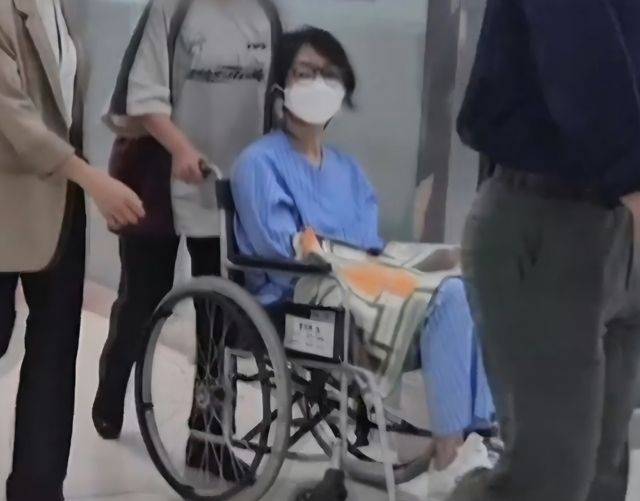 Former first lady Kim Keon Hee, in a blue detainee uniform with a mask and glasses, is escorted through hospital corridors on Thursday. (MBN)