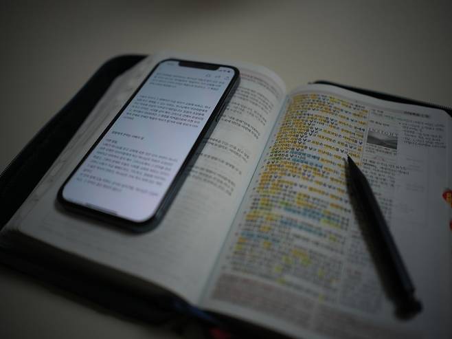 최 원장이 딸들에게 매일 보내는 묵상글 이미지. 휴대전화 밑의 책은 평소 그가 사용하는 성경책이다. 최 원장 제공