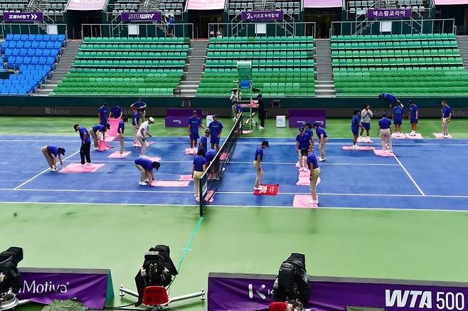 우천 후 경기 재개를 위해 코트 바닥을 정리하고 있는 스탭들