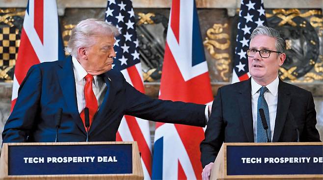 AFP 연합뉴스18일 영국을 국빈 방문한 도널드 트럼프(왼쪽) 미국 대통령이 미·영 정상회담에 이은 공동 기자회견 도중 키어 스타머 영국 총리의 등을 두드리고 있다. 강연대에 적힌 ‘Tech Prosperity Deal’은 이날 두 정상이 서명한 ‘기술 번영 협정’으로,  첨단 기술 분야에서 양국이 협력을 강화한다는 내용이 담겼다.