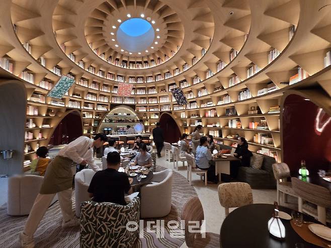 “르 카페 루이비통” 내부 전경. 돔형 천장과 책장형 인테리어가 어우러진 도서관 콘셉트 공간에서 손님들이 식사를 즐기고 있다. (사진=김지우 기자)