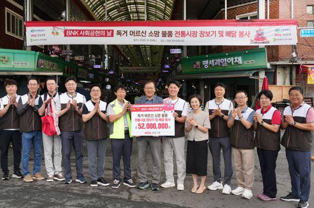 20일 창원 명서시장에서 김태한(오른쪽 여섯 번째)BNK경남은행장이 장금용(오른쪽 일곱 번째)창원시장권한대행에게'독거 어르신 소망 물품 기탁 증서'를 전달하고 있다.BNK금융그룹 제공