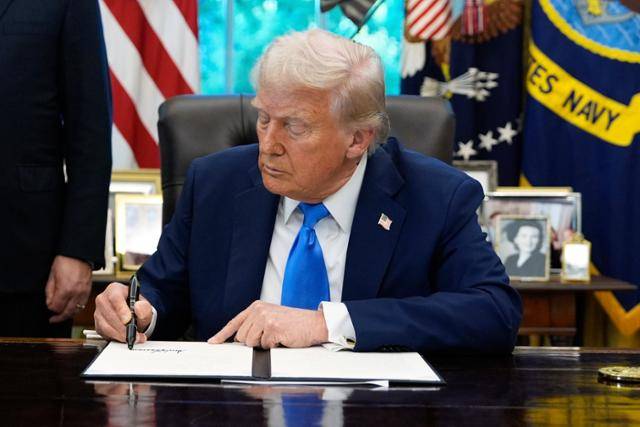 도널드 트럼프 미국 대통령이 19일 미 워싱턴 백악관 집무실에서 행정명령에 서명하고 있다. 워싱턴=AP 뉴시스