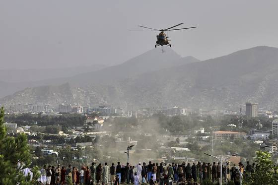 지난 8월 15일 아프가니스탄 수도 카불에서 열린 미국 철수 및 탈레반 통치 시작 4주년을 기념하는 행사에서 군용 헬리콥터가 도시 상공에 꽃을 떨어뜨리고 있다. AP=연합뉴스