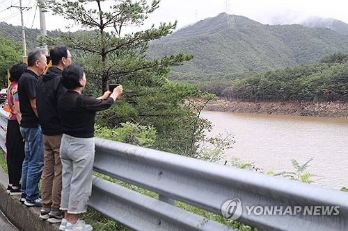 지난 20일 강원 강릉시의 주요 상수원인 오봉저수지를 찾은 시민들이 상류에서 물이 유입되면서 수위가 오르는 모습을 보며 기뻐하고 있다. 연합뉴스