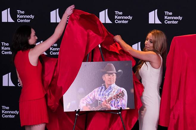 13일(현지시간) 도널드 트럼프 미국 대통령이 케네디 센터에서 열린 행사에서 올해 케네디 센터 명예의 전당 수상자 후보를 발표하는 가운데, 컨트리 음악가 조지 스트레이트의 사진이 공개되고 있다. [AFP]