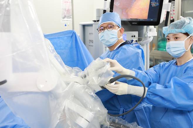 정두용 인하대병원 비뇨의학과 교수(왼쪽)가 방광절제 로봇수술을 앞두고 환자와 수술 로봇을 연결하는 ‘도킹’ 작업을 하고 있다. 인하대병원 제공