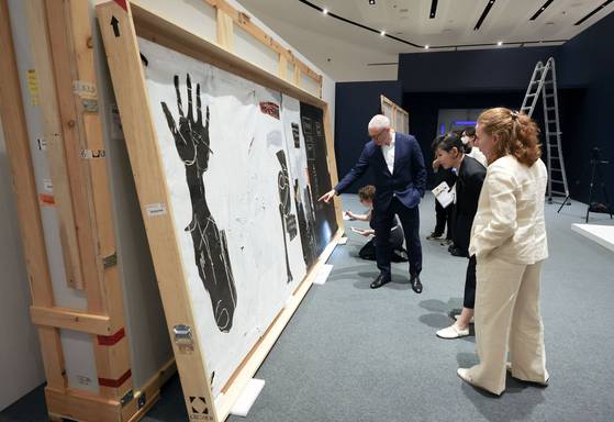 18일 오후 서울 동대문디자인플라자 전시1관에서 장 미셸 바스키아의 '육체와 영혼' 아랫부분을 쿠리에, 보존처리인들과 함께 살펴보는 큐레이터들. 김성룡 기자