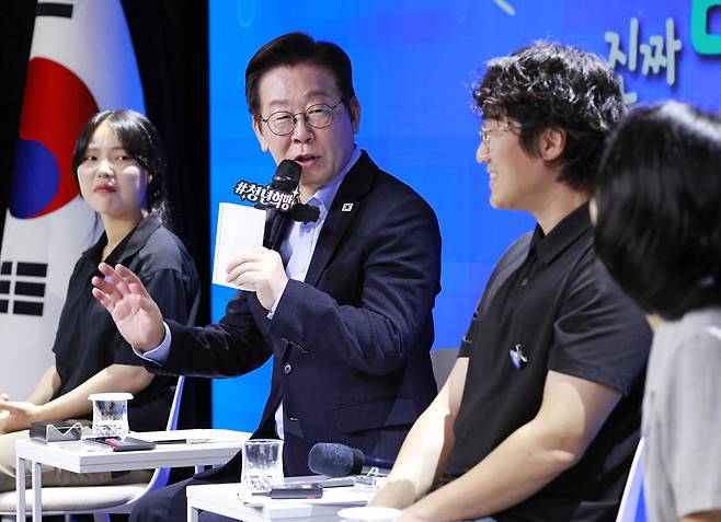 President Lee Jae Myung ,second from left, talks with a participant at an event held to communicate with people in their 20s and 30s held at a theater in Seoul on Sept. 19. (Yonhap)
