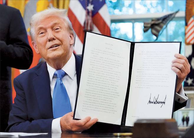 미국 전문직 비자인 H-1B 비자의 수수료를 1인당 10만 달러(약 1억40000만원)로 대폭 인상하는 정책이 발표되며 혼란이 이어지자 하루 뒤인 20일(현지시간) 신규 비자 신청자에게만 적용된다고 밝히는 등 트럼프 행정부가 진화에 나섰다. 사진은 도널드 트럼프 미 대통령이 지난 19일 워싱턴 D.C. 백악관 오벌오피스에서 골드카드 비자 행정명령에 서명한 문서를 들어 보이고 있는 모습 [로이터]