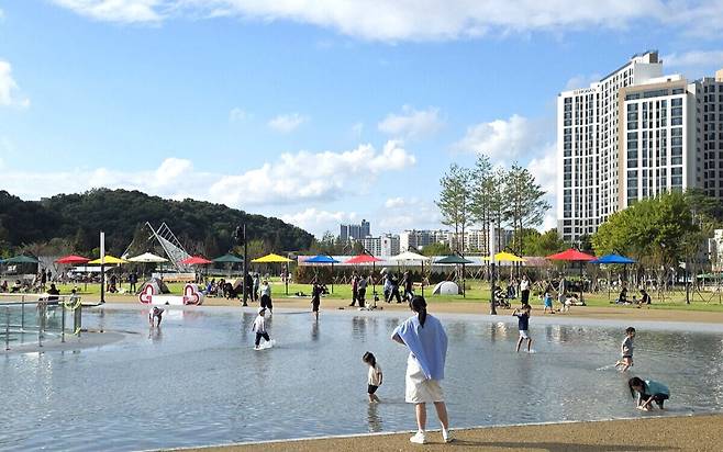 시기와 계절에 따라 음악분수, 바닥분수, 물놀이장, 거울연못, 광장으로 변신하는 수변공원에서 얕은 물을 걸으며 물놀이를 즐기는 아이들.