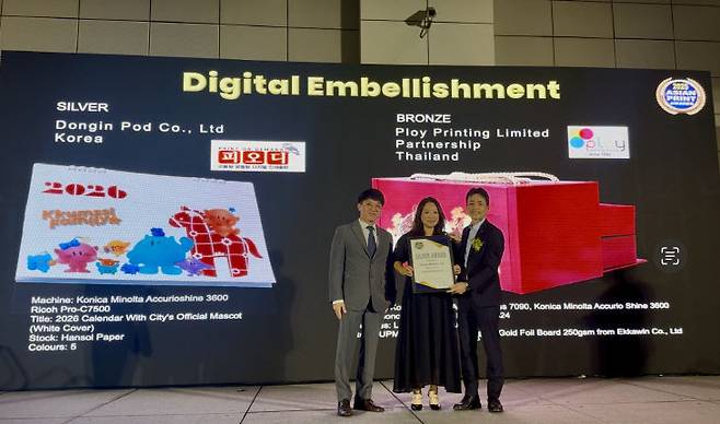 최은서 동인피오디 대표<사진 가운데>가 지난 19일 태국 방콕에서 열린 '아시안 프린트 어워드(Asian Print Awards·이하 APA) 2025'에서 디지털 장식 부문(Digital Embellishment) 은상과 디지털 캘린더 부문(Digital Calendars) 동상을 수상한 뒤 기념촬영하고 있다. 동인피오디는 이번 시상식에 앞서 대전의 마스코트인 꿈씨패밀리(꿈돌이)를 활용한 2026년 캘린더를 2개 부문에 출품했다. /동인피오디 제공