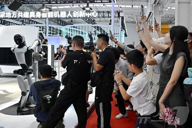 중국 베이징에서 개최된 로봇박람회 관람객들이 유비테크의 워커S2가 스스로 배터리를 교환하는 장면을 지켜보고 있다. 2025.8.8 ⓒ AFP=뉴스1 ⓒ News1 정은지 특파원