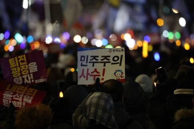 지난해 12월7일 오후 서울 여의도 국회 앞에서 열린 ’내란죄 윤석열 퇴진! 국민주권 실현! 사회대개혁! 범국민 촛불대행진’에서 참석자들이 “민주주의 사수” 등 손팻말과 형형색색의 응원봉을 들고 있다. 연합뉴스
