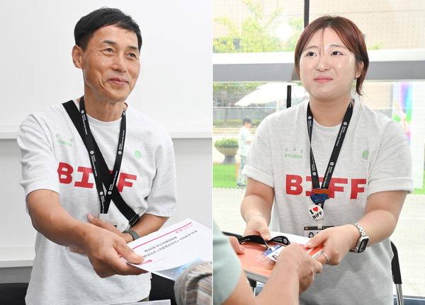 제30회 BIFF 자원봉사자로 참여한 이병훈(왼쪽) 씨와 윤수희 씨가 영화제를 찾은 게스트에게 책자를 건네며 미소를 짓고 있다.  김정록 기자